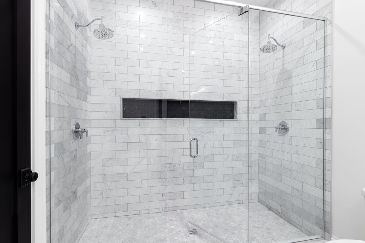 Luxury double shower with marble subway tile walls and marble hexagon floor restored by MarbleBLU