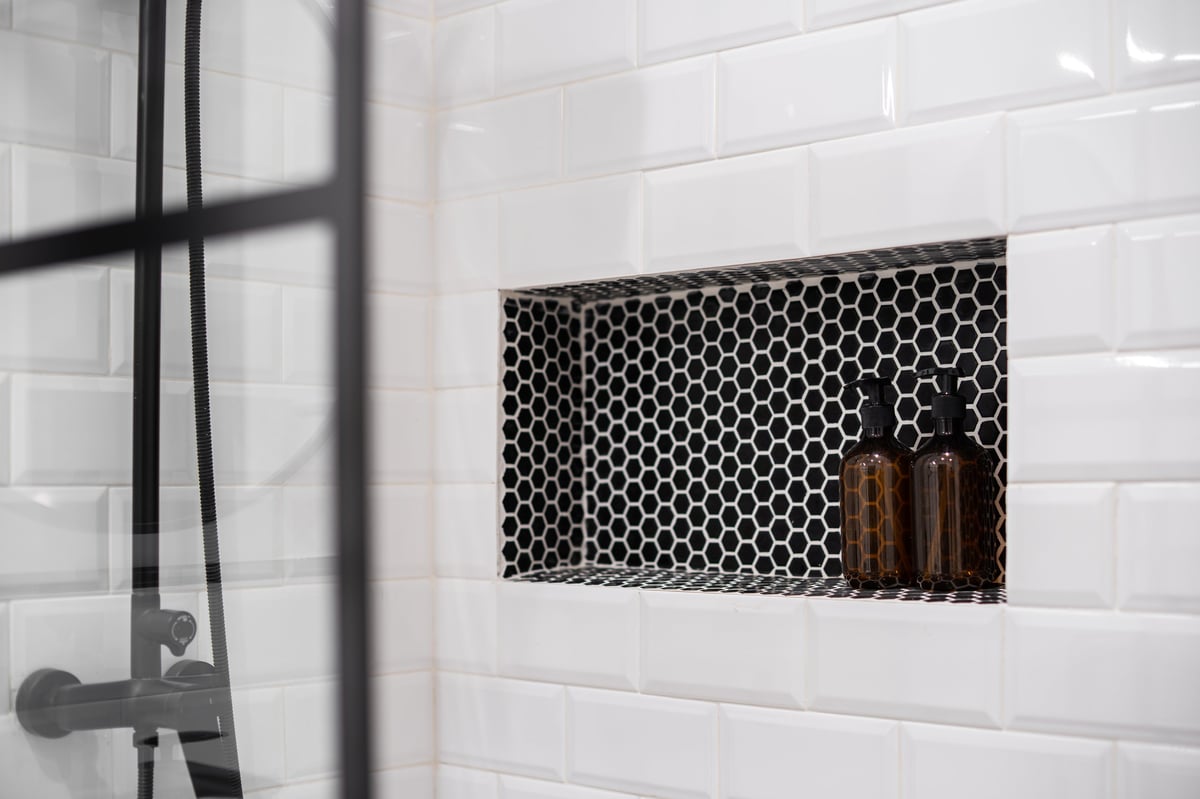 Built-in shower shelf with white wall tiles after grout repair and sealing