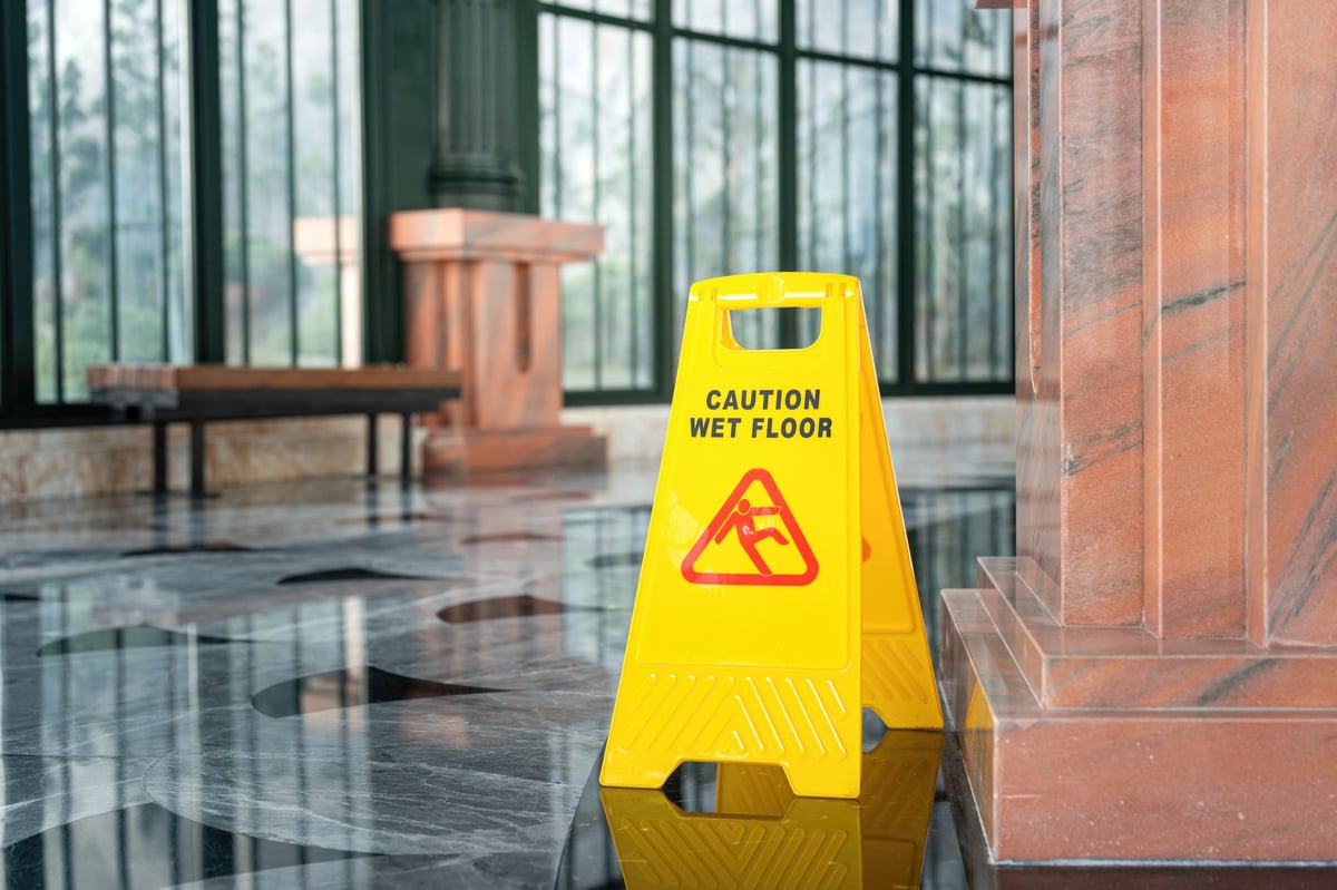 Hotel marble floor with wet floor warning sign - slip hazard in commercial building