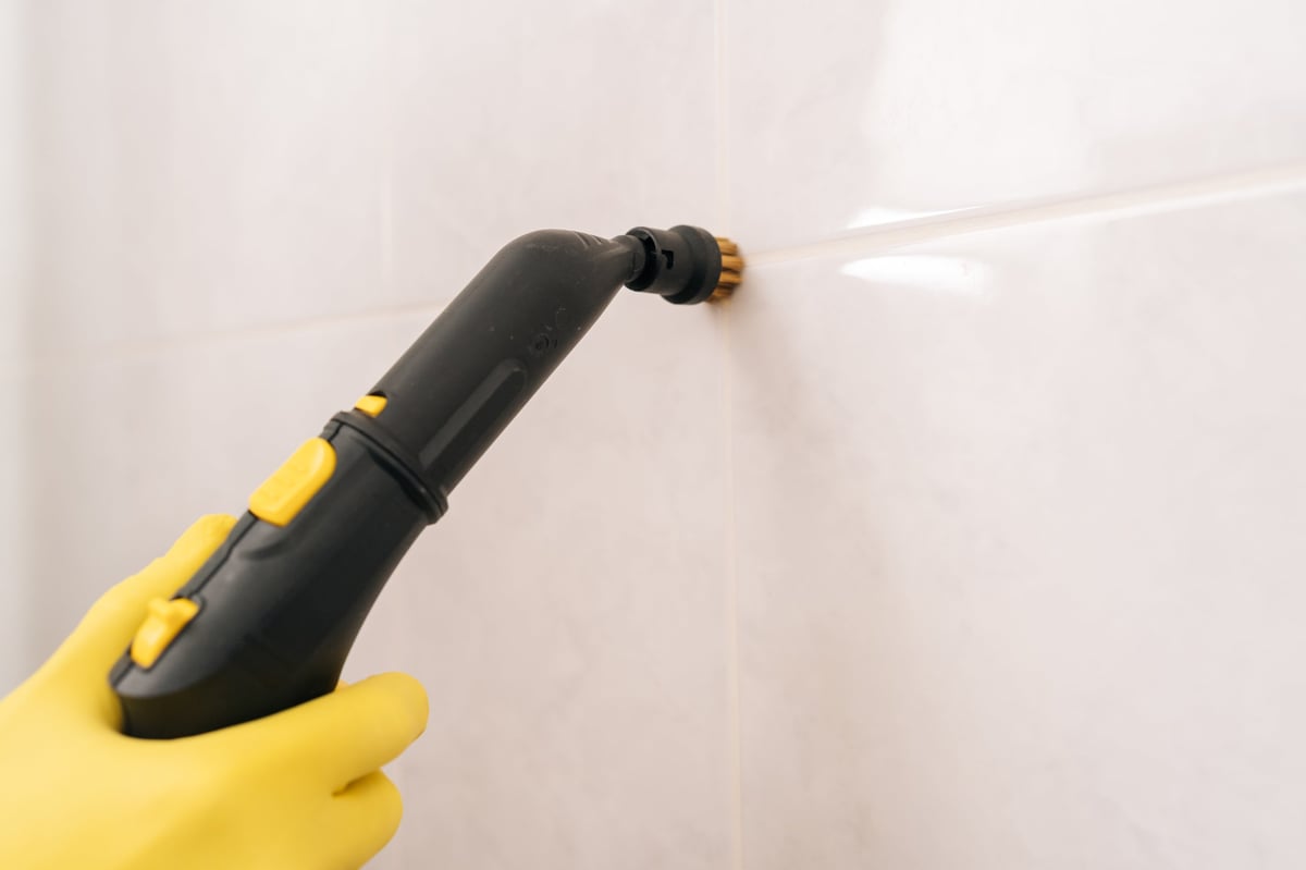 Close-up of grout lines between white tiles being cleaned and restored