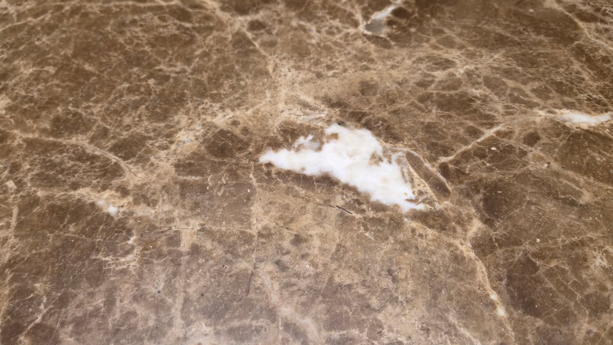Close-up of polished brown marble featuring intricate white veining and natural mineral patterns.