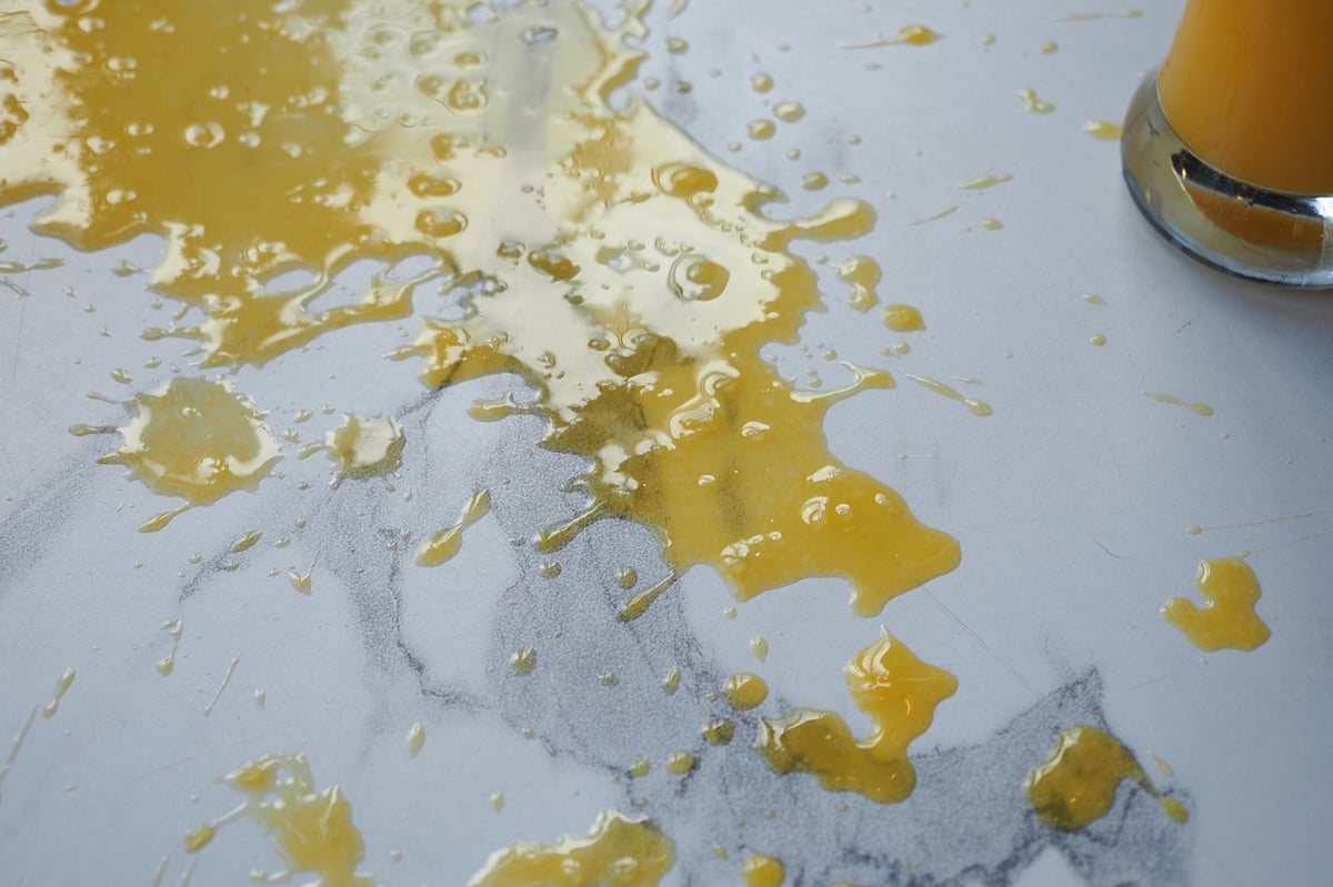 Juice is spilled on a marble countertop in a kitchen space.